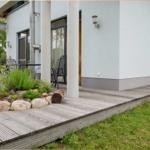 Terrasse mit Sitzgruppe und Pflanzenbeet vor modernem Haus