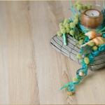 Holztisch mit Kerzen, Schalentier und grüner Dekoration.