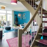 Eingangsbereich mit Treppe und Blick in Wohnzimmer mit blauer Wand und Kamin.