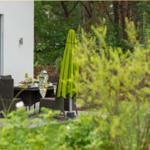 Gartenbereich mit gedecktem Tisch und grünem Sonnenschirm