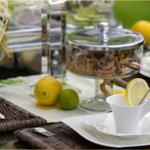 Tisch gedeckt mit Tassen, Zitronen und Keksen in Glasbehälter.