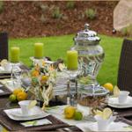 Garten-Tisch mit Tassen, Zitronen und Kerzen für Gäste