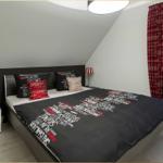 Schlafzimmer mit Dachschrägen, Bett mit Kissen und Vorhängen.