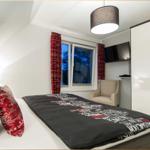 Schlafzimmer mit Bett, Fenster, Kleiderschrank und Sessel.