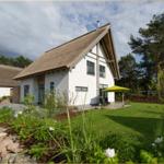 Wohnhaus mit strohgedecktem Dach, Garten und gelber Sonnenschutz