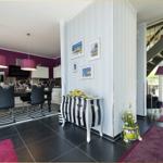 Essbereich mit Tisch, Stühlen und Küchenzeile. Treppenhaus und Wohnbereich sind sichtbar.