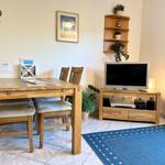 Essbereich mit Holztisch, Fernseher und Blau-Teppich