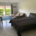 Schlafzimmer mit Sofa, Bett und Glastür zum Garten.