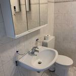 Badezimmer mit Waschbecken, Toilette und Spiegel.