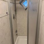 Dusche mit Duschwanne, Duschbrause und Dachfenster.