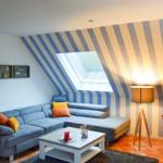 Wohnzimmer mit Sofa, Couchtisch und gestreifter Wand unter Dachschrägen.