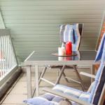 Terrasse mit Tisch und zwei Stühlen mit Kissen und Kerzen.