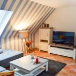 Wohnzimmer mit Sofa, Fernseher und Dachfenster. Wand mit Streifenmuster.