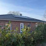 Ein Einfamilienhaus mit rotem Backstein und dunklem Dach unter blauem Himmel.