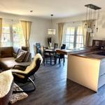 Raum mit gemütlicher Sitzecke und 65 Zoll TV Offener Küche mit Tresen und Kochinsel. Essecke mit 6 Plätzen. Blick auf die Felder. und d...