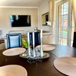 Raum mit gemütlicher Sitzecke und 65 Zoll TV Offener Küche mit Tresen und Kochinsel. Essecke mit 6 Plätzen. Blick auf die Felder. und d...