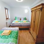 Zimmer mit zwei Betten, Holzschrank und Fenster.