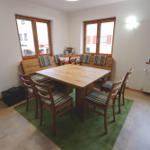 Esszimmer mit Holztisch, Sitzbank und Stühlen auf grünem Teppich