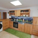 Küche mit Holzmöbeln, Spüle, Kochfeld und Waschmaschine.