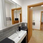 Badezimmer mit Waschbecken, Spiegelschrank und Tür zum Bad