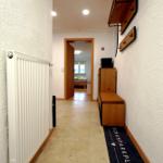 Flur mit Heizkörper, Wandregal und Schuhmatte zum Schlafzimmer.