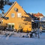 Ein zweistöckiges Haus mit Schnee bedecktem Garten und Satellitenschüssel.