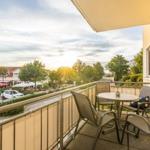 Terrasse mit Tisch und Stühlen. Blick auf Straße und Bäume bei Sonnenuntergang.