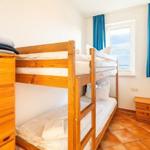 Zimmer mit Doppelstockbett, Holzschrank und Fenster mit Blick aufs Meer.