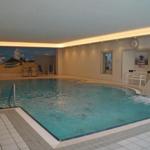 Innenpool mit Wasserfall und Strandbild an der Wand.