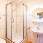 Badezimmer mit Dusche, Waschbecken und Spiegel