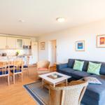 Wohn- und Essbereich mit Sofa, Esstisch und Küche.