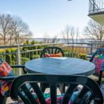 Terrasse mit Tisch und Stühlen, Blick auf Wasser und Bäume.