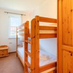 Ein Schlafzimmer mit Holz-Etagenbett, Kleiderschrank und Fenster.