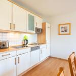 Küche mit weißen Schränken, Holzoberfläche und Küchengeräten.