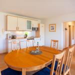 Essbereich mit runden Tisch und Stühlen, Küche mit weißen Schränken und Mikrowelle.