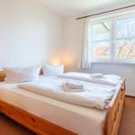 Ein Schlafzimmer mit einem Holzbett, weißen Bettwäsche und einem Fenster mit Vorhängen.