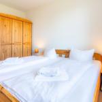 Schlafzimmer mit Holzbett, Kleiderschrank und Nachttisch mit Lampe.