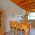 Essbereich mit Holztisch und Stühlen. Küche mit Arbeitsplatte und Fenster.