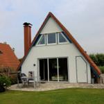 Wohnhaus mit Terrasse und Garten. Große Glastüren führen ins Innere.