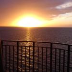 Sonnenuntergang über dem Meer von einer Balkonterrasse aus gesehen.