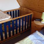 Kinderbett mit Wickelplatz und Nachttisch mit Lampe und Wecker.