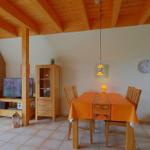 Esszimmer mit Holztisch, Stühlen und Kaminofen an der Wand.