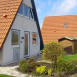 Wohnhaus mit Terrasse und Garten. Hinterhof mit Holzgarage und Rasenfläche.