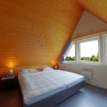 Schlafzimmer mit Doppelbett, Kinderbett und Fenster mit Blick.