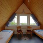 Zimmer mit zwei Betten, Holzwand und Fenster mit Blick nach draußen.