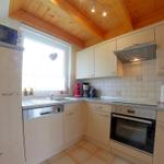 Küche mit Holzdecke, hellen Schränken und moderner Ausstattung.