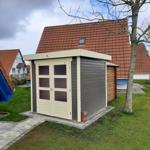 Holzgarage mit Doppeltür und Dachfenster im Garten.