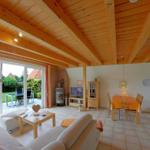 Wohn- und Essbereich mit Holzdecke, Couch, Esstisch und Blick auf den Garten.