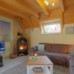 Wohnzimmer mit Sofa, Kamin und Fernseher unter Holzbalkendecke