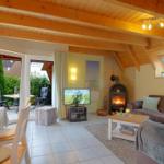 Wohn- und Essbereich mit Holzdecke, Kamin und Blick auf den Garten.